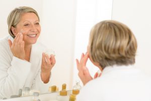 mature woman applying skin care product
